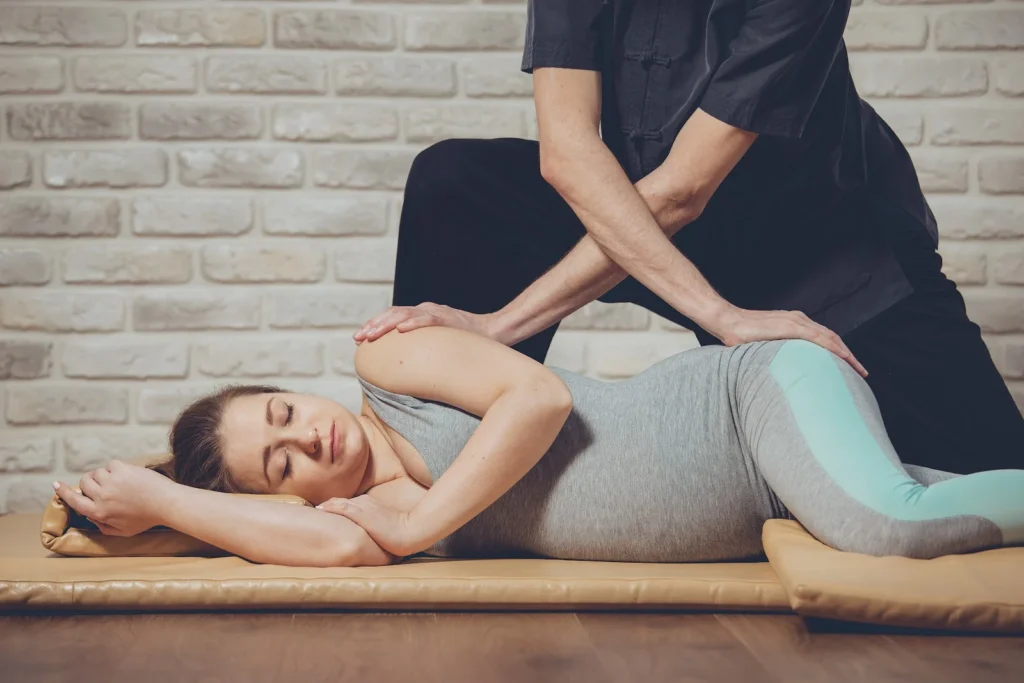 A pregnant woman lying on her side while getting massaged