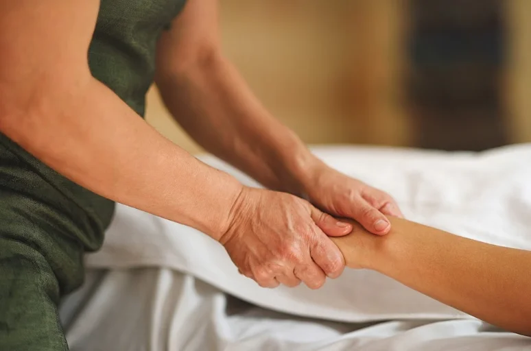 Hands of masseur pressing hands of patient
